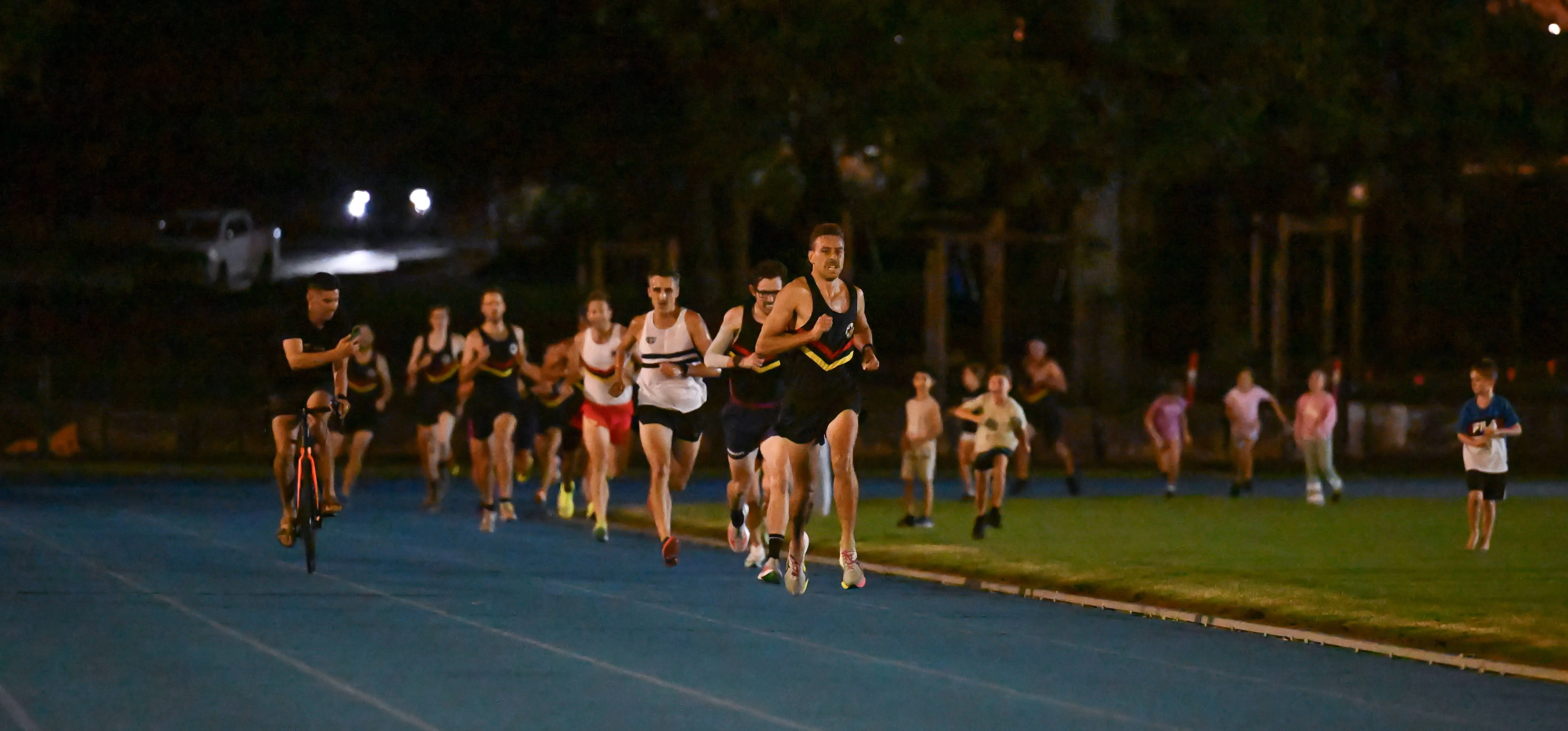 The field strung out around the bend of the track at night